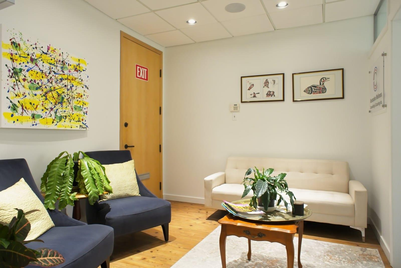 The waiting room of a Restorative Wellness office, with a sofa, two armchairs and plants
